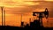 Silhouette of oil pumpjack at sunset. Oil and gas industry equipment.