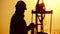 Silhouette of oilfield worker at crude oil pump in the oilfield at golden sunset. Industry, oilfield, people and