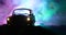 Silhouette of old vintage car in dark foggy toned background with glowing lights in low light, or silhouette of old crime car dark