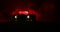 Silhouette of old vintage car in dark foggy toned background with glowing lights in low light, or silhouette of old crime car dark