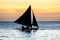 Silhouette of outrigger sailboat at sunset