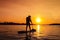 Silhouette paddle board surfer at sunset. Man boating ride on city river. Concept of outdoor activities