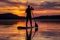 silhouette of paddleboarder against sunset reflections on lake