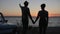 Silhouette of pair That holding hands and Looks in evening sundown Outdoors, romantic Trip of Lovers to seafront