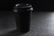 A silhouette of a paper refillable coffee Cup with a closed lid on a black background