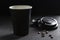 A silhouette of a paper refillable coffee Cup with an open lid and coffee beans on a black background