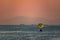 Silhouette of a parachute and a skydiver against the background of a bright burning sunset over the sea