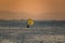 Silhouette of a parachute and a skydiver against the background of a bright burning sunset over the sea