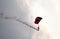 Silhouette parachute stunt unfocused and blurry while gliding in the air with red smoke trail during an air exhibition