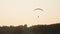 Silhouette of paramotor flying close over trees