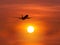 Silhouette passenger airplane flying above the sun during sunset