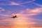 Silhouette passenger airplane flying away in to sky high altitude during sunset time