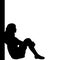 Silhouette of pensive girl sitting by the wall