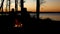 Silhouette of people enjoyiing beautiful lakeside campfire just after sunset with trees along Minnesota lake shoreline