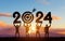 Silhouette people holding numbers 2024 with colorful dramatic sky at sunset. Hit the target. Concept for success in the future