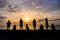 Silhouette of people relaxing watching colourful sunrise at a beach