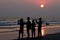 Silhouette of people taking sunset picture on beach