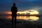 Silhouette of a person in the beach at sunrise. Young woman standing alone in solitude watching the burning sky light over sea