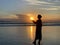 Silhouette of the person in the beach at sunset background. Woman standing alone with sun in hands.