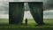 Silhouette of person behind green curtain looking out of stormy grassy landscape
