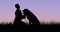 Silhouette person kneeling on grass while holding puppy at dusk against clear sky with copy space