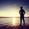 Silhouette of person in sportswear on beach seeing into morning Sun