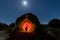 Silhouette of a person standing near an illuminated rock in Los Barruecos