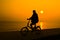 Silhouette of person who rides a bicycle near sea water with the s