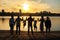 The silhouette photo of big family with the grandmother and small children on walk on the river bank in the sunset sun