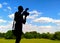 Silhouette of photographer with camera against the background of green clipped lawn