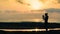 silhouette of a photographer girl in the rays of the rising sun on the beach