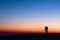 Silhouette of photographer standing on hill and making photo of evening valley