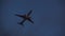 Silhouette of plane flying through evening sky. Fast airplane departing to place of destination in dusk. Concept of