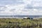 The silhouette of the plant on the horizon with smoking pipes and an old fuel truck, riding on the field, against the cloudy sky