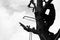 Silhouette portrait of arborist holds on the tree with hand saw with clear sky background processed in monochrome tone