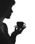 Silhouette portrait of a female with a cup of hot drink on a saucer