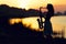 Silhouette portrait of a woman in a dress whose hobby music, she plays on the river bank and is resting emotionally