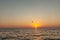 Silhouette of powered paraglider soaring flight over the sea against marvellous orange sunset sky. Paragliding - recreational and