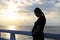 Silhouette pregnant woman embracing her belly on the seashore at sunset