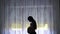 Silhouette of pregnant woman watching the window