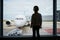 Silhouette of a preschooler girl in international airport, looking through the window at planes