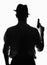 Silhouette of private detective with a gun in right hand. Agent stay back to camera. Criminal scene in black and white