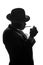 Silhouette of private detective lights cigarette. Agent looks like Al Capone stay side to camera. Police criminal scene in black