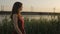 Silhouette profile of beautiful girl walking along the riverbank with reeds at sunset, cute woman walks in nature in summer, roman