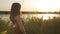 Silhouette profile of beautiful girl walking along the riverbank with reeds at sunset, cute woman walks in nature in summer, roman