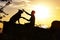 Silhouette profile of hapy man and dog sitting and playing on nature, boy training German Shepherd at sunset in a field, concept