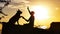 Silhouette profile of a training German Shepherd dog with a handler at sunset in a field, tamer man establishes a trusting