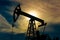 Silhouette of a pumpjack on an oil well against the background of an alarming sky