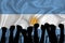 Silhouette of raised arms and clenched fists on the background of the flag of Argentina. The concept of power, power, conflict.