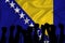 Silhouette of raised arms and clenched fists on the background of the flag of bosnia and herzegovina. The concept of power,